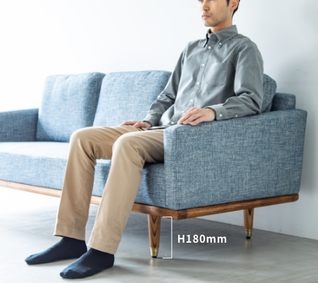 脚の高さ180mmに175cmの男性がソファFOLKEフォルケに座っている一例